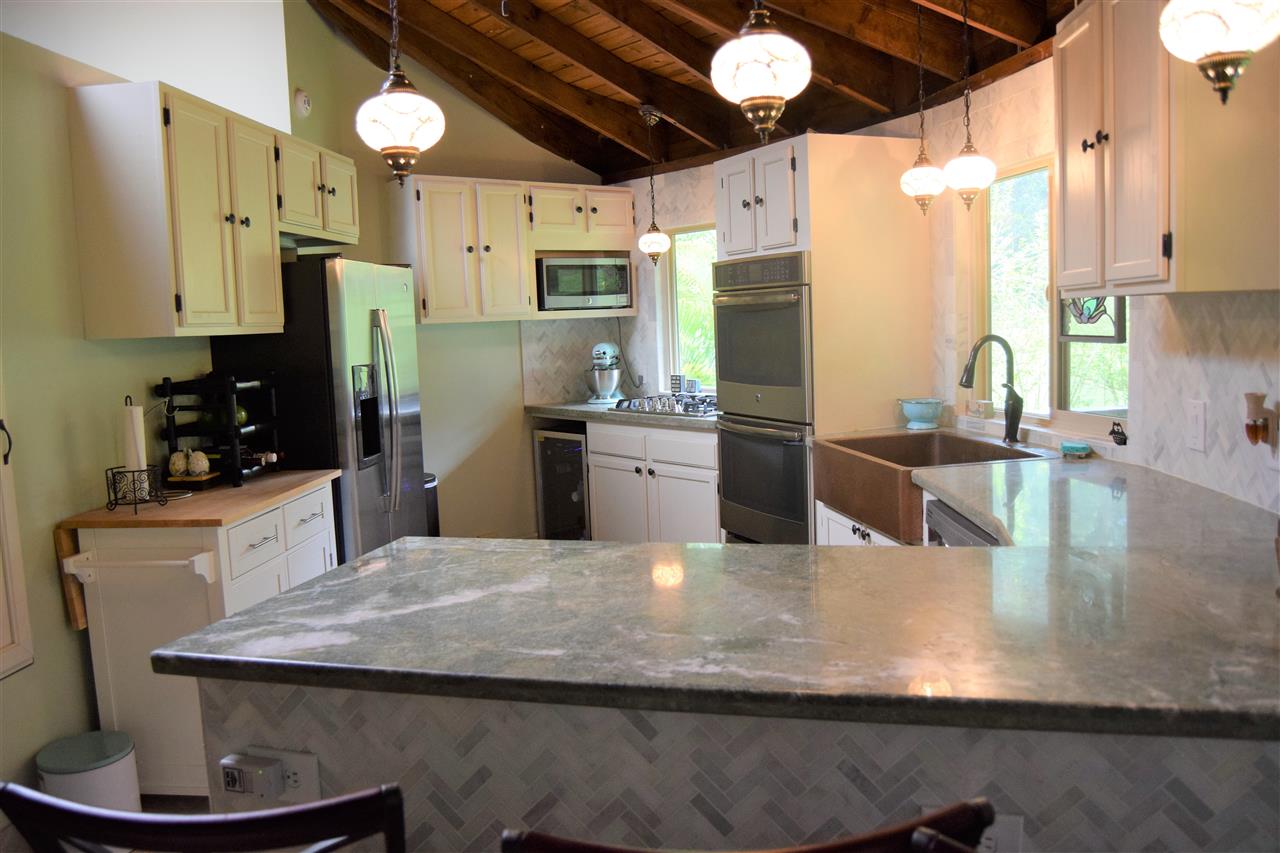 301 Kalipo Place Haiku, HI 96708 - Photo 4 of 30 a kitchen with stainless steel appliances kitchen island granite countertop a refrigerator a stove and a sink with wooden floor