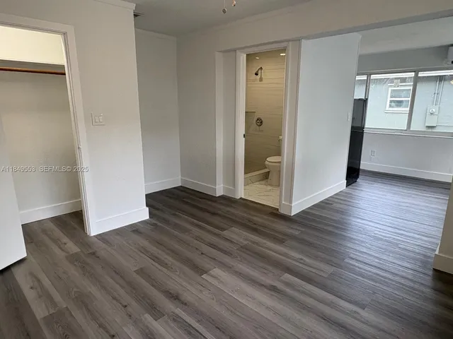 an empty room with wooden floor & windows and bathroom