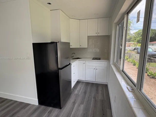 a kitchen with a refrigerator a sink and dishwasher with wooden floor