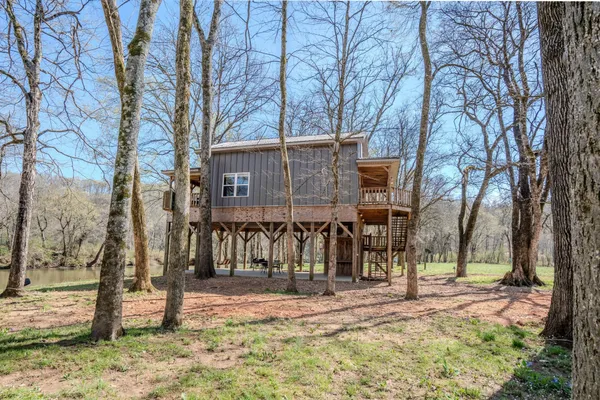 a view of a wooden house with large trees