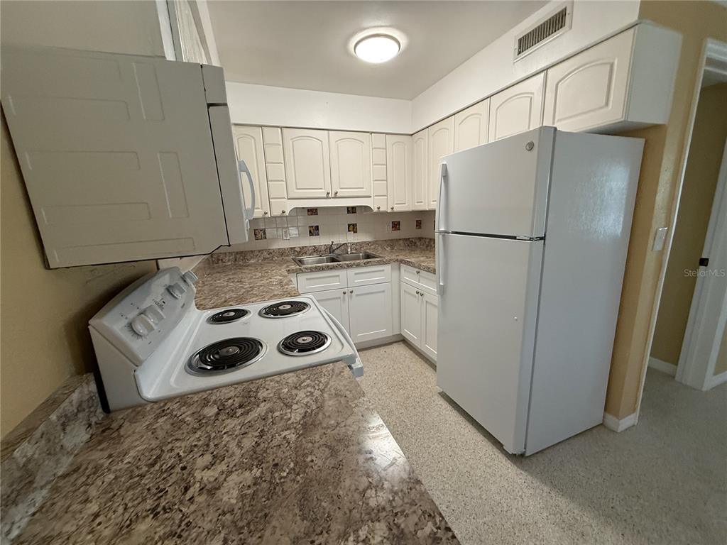 17688 Gulf Boulevard, Unit 104 Redington Shores, FL 33708 - Photo 7 of 15 a kitchen with a refrigerator a stove a sink and cabinets