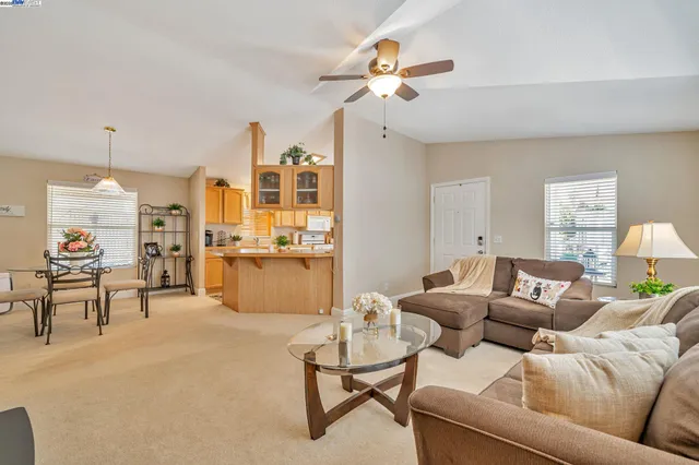 a living room with furniture kitchen view and a chandelier