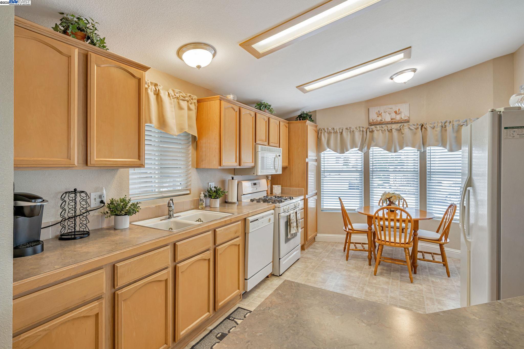 3263 Vineyard, Unit 68 Pleasanton, CA 94566 - Photo 10 of 41 a kitchen with a sink chairs and wooden cabinets