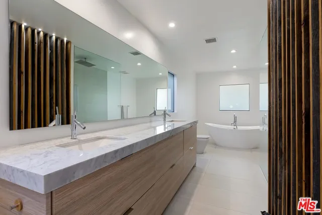a bathroom with a granite countertop sink a large mirror and a bathtub