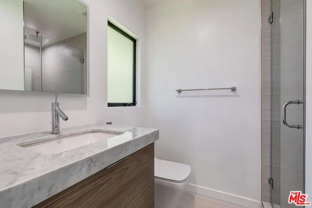 a bathroom with a granite countertop sink toilet and mirror