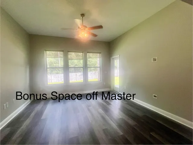 an empty room with a chandelier fan and windows