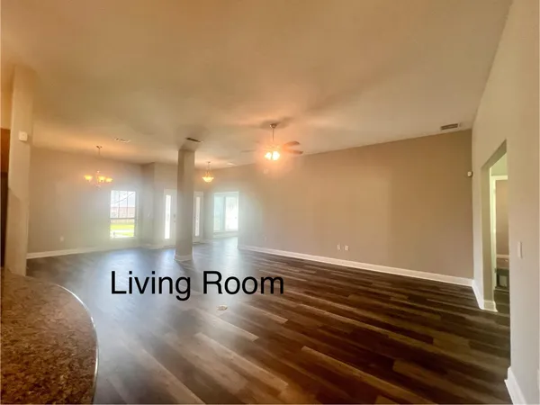 a view of an empty room with window and wooden floor