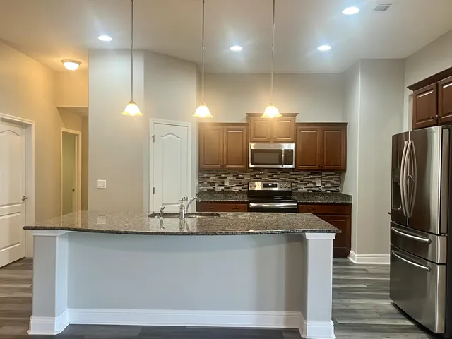 a kitchen with stainless steel appliances granite countertop a sink and a refrigerator
