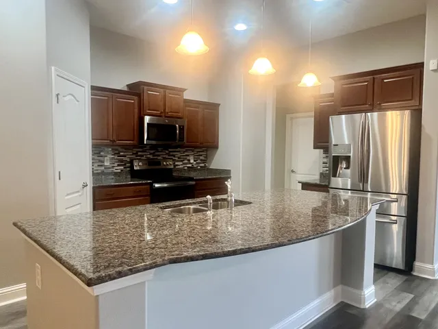 a kitchen with kitchen island granite countertop lots of counter top space and stainless steel appliances