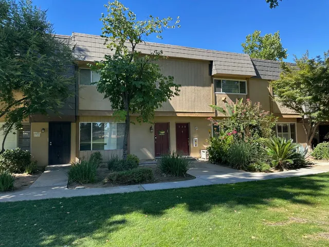 a front view of a house with a yard and potted plants