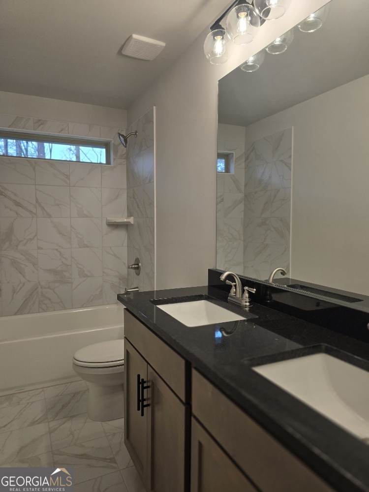 128 Patillo Manor, Unit 7 Stockbridge, GA 30281 - Photo 26 of 37 a bathroom with a granite countertop sink a toilet a bathtub and shower