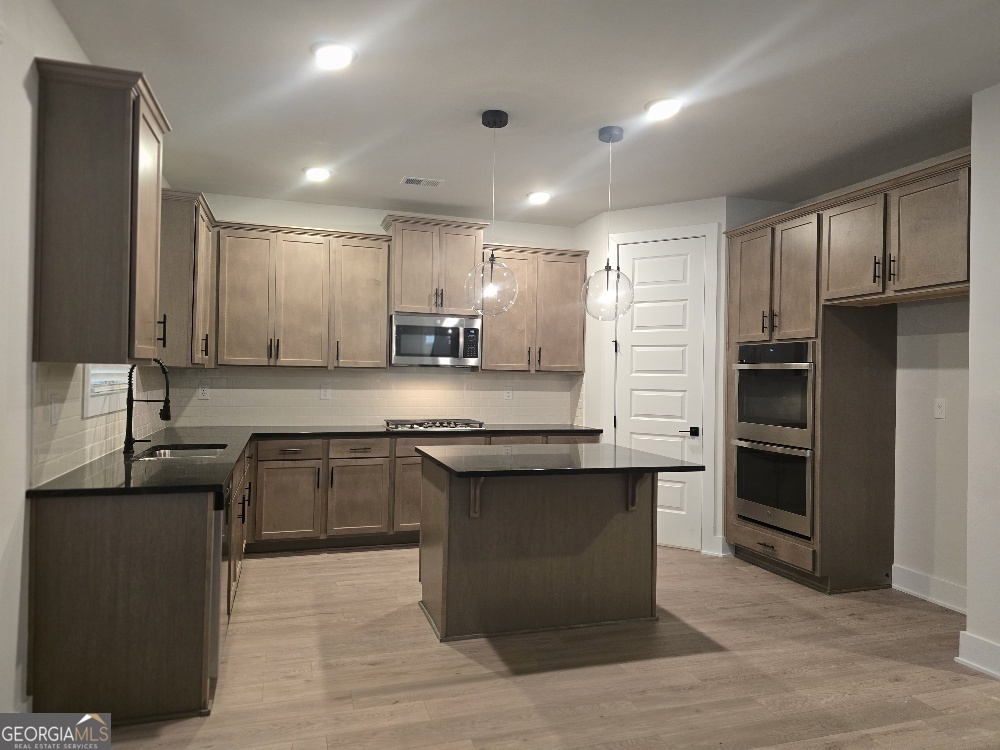 128 Patillo Manor, Unit 7 Stockbridge, GA 30281 - Photo 8 of 37 a large kitchen with stainless steel appliances kitchen island granite countertop a refrigerator and a stove top oven