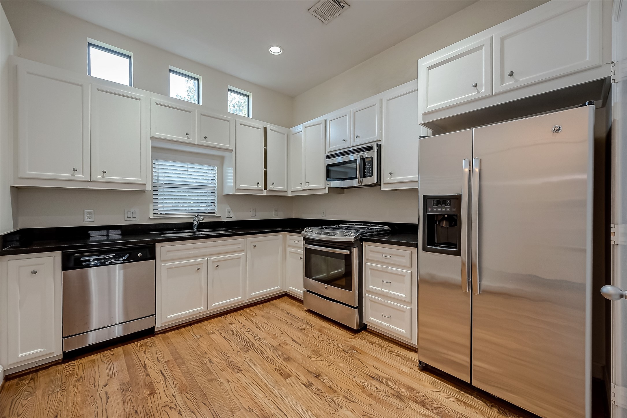 2710 Hullsmith Drive, Unit 1503 Houston, TX 77063 - Photo 6 of 14 a kitchen with granite countertop a refrigerator stove and white cabinets