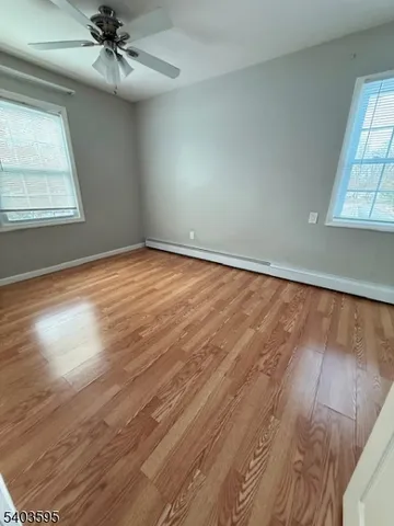 en empty room with wooden floor fan and windows