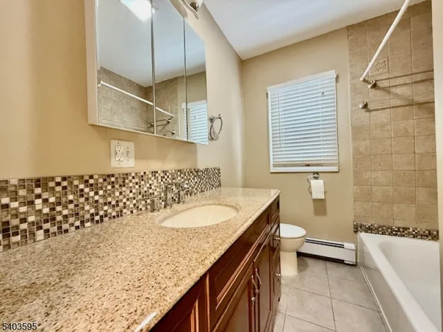 a bathroom with a granite countertop sink a toilet and bathtub