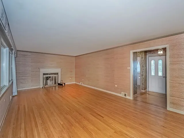 a view of empty room with wooden floor and fireplace