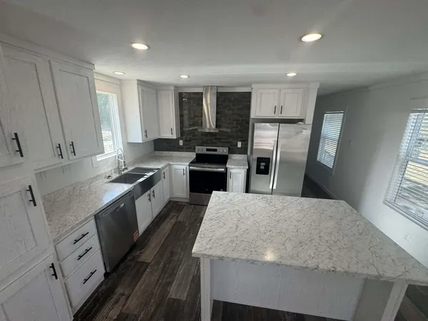 a large kitchen with granite countertop a large counter top appliances and cabinets