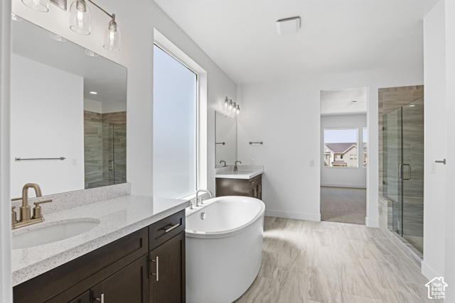 79 South Crimson Way West, Unit 307 Mapleton, UT 84664 - Photo 35 of 42 Dual vanity with undermount sinks, a freestanding soaking tub, a frameless glass shower enclosure, wood-finish flooring, and a large frosted window