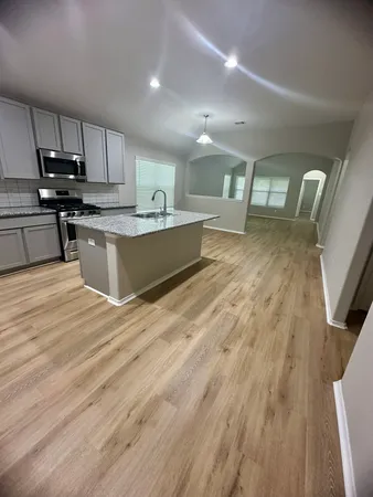a large kitchen with stainless steel appliances wooden floors and view living room