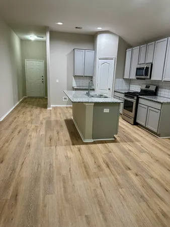 a kitchen with granite countertop a stove a sink and a refrigerator