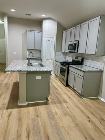 a kitchen with stainless steel appliances granite countertop a sink a stove a refrigerator and cabinets