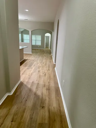 a view of a hallway with wooden floor and a bathroom