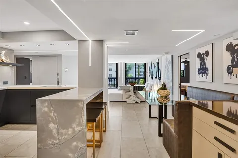 a living room with stainless steel appliances furniture a rug and a view of kitchen