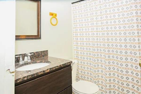 a bathroom with a granite countertop toilet sink and mirror