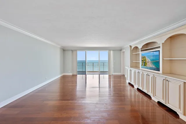 a view of an empty room with wooden floor and windows