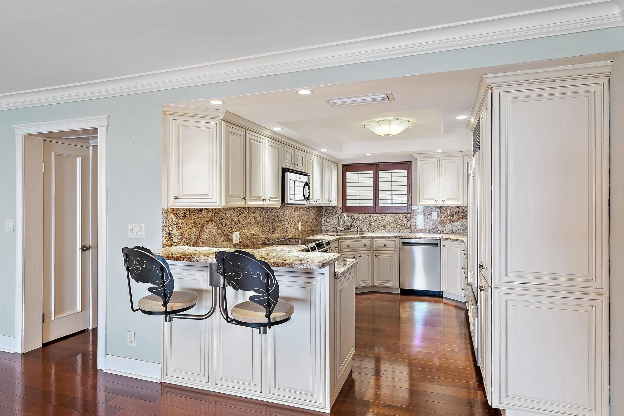 350 South Beach Road, Unit 503 Tequesta, FL 33469 - Photo 15 of 51 a kitchen with stainless steel appliances granite countertop a stove top oven a sink and white cabinets with wooden floor