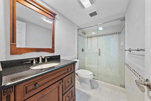 a bathroom with a sink a toilet a mirror and shower