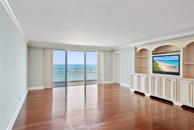 a view of an empty room with wooden floor and windows