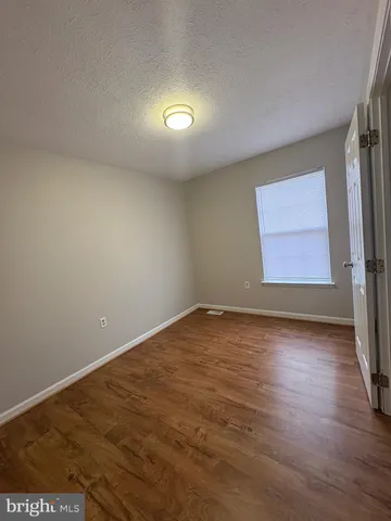 an empty room with wooden floor and window