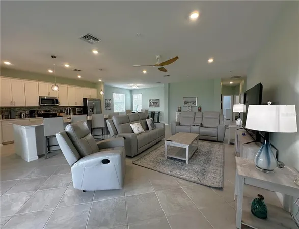 a living room with couches and kitchen view with wooden floor