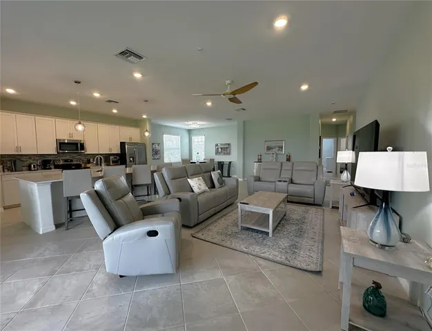 a living room with couches and kitchen view with wooden floor