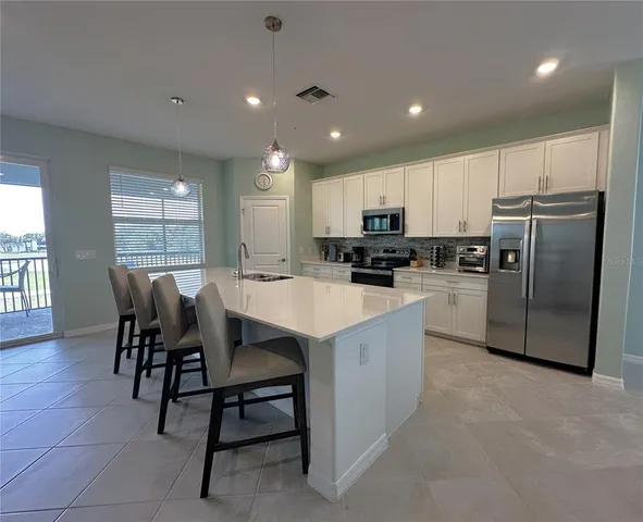 a kitchen with stainless steel appliances granite countertop a table chairs sink refrigerator and microwave
