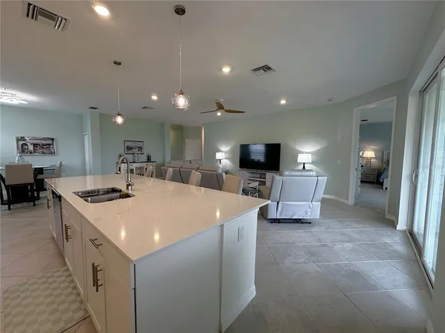 a large white kitchen with a large screen tv and couches