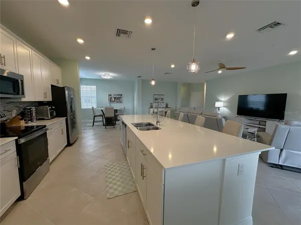 a large white kitchen with a large island in the center