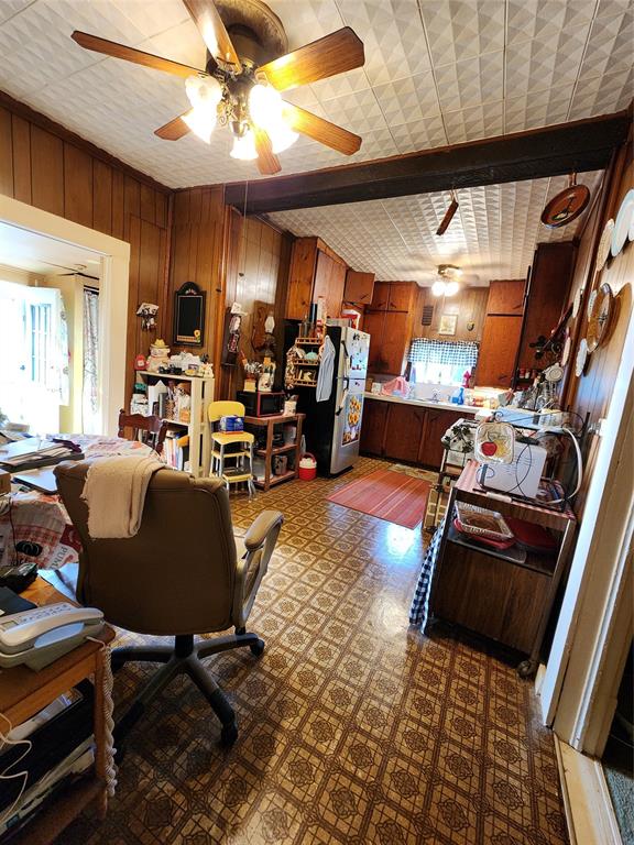 403 Barker Street Cumby, TX 75433 - Photo 5 of 16 Open-concept living space featuring wood paneling, patterned ceiling tiles, and a multi-light ceiling fan
