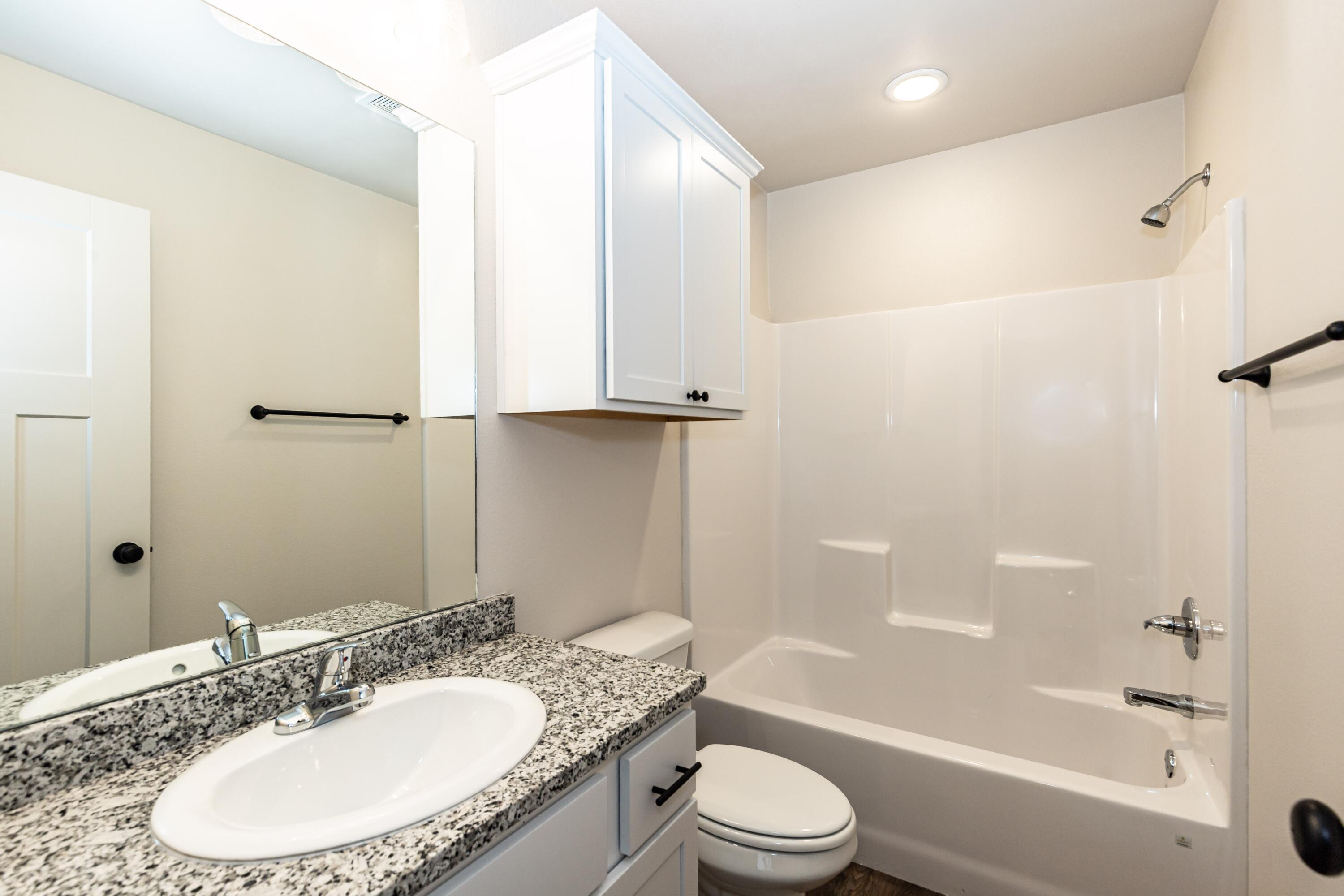 2529 138th Street Lubbock, TX 79423 - Photo 17 of 24 a bathroom with a granite countertop sink a toilet and shower