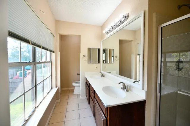 a en suite bathroom with a double vanity sink a large mirror and a bathtub