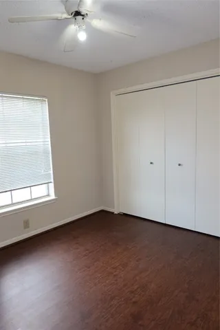 an empty room with a ceiling fan and windows