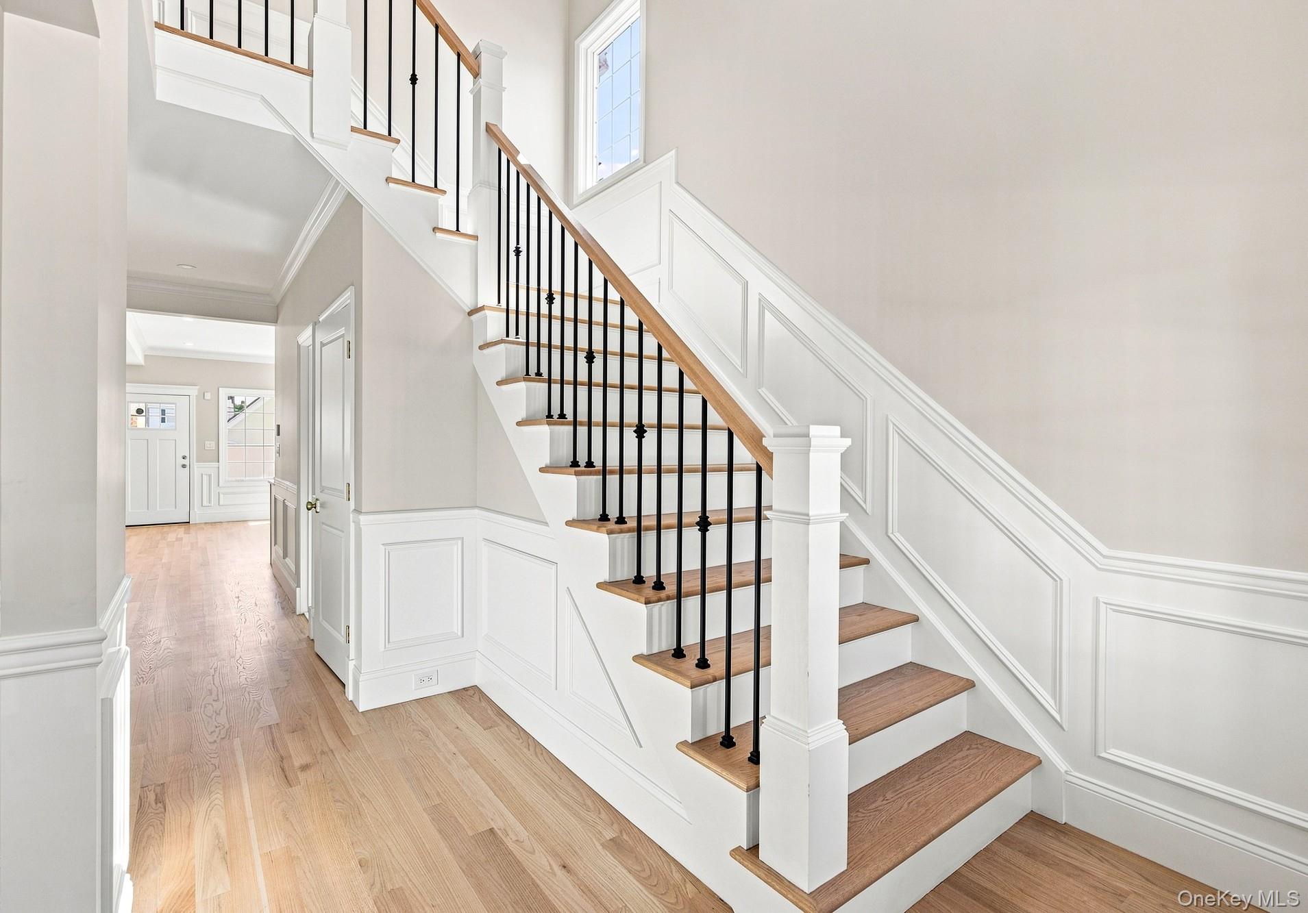 148 Latham Road Mineola, NY 11501 - Photo 17 of 27 Light and Bright entryway and stairs to second floor Hardwood flooring, wainscoting, solid panel doors, wood-finish stair treads, and wrought iron balusters.
