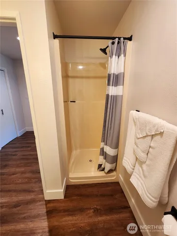 a view of front door with wooden floor and a shower