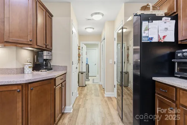 a kitchen with stainless steel appliances granite countertop a refrigerator a sink dishwasher and wooden cabinets with wooden floor