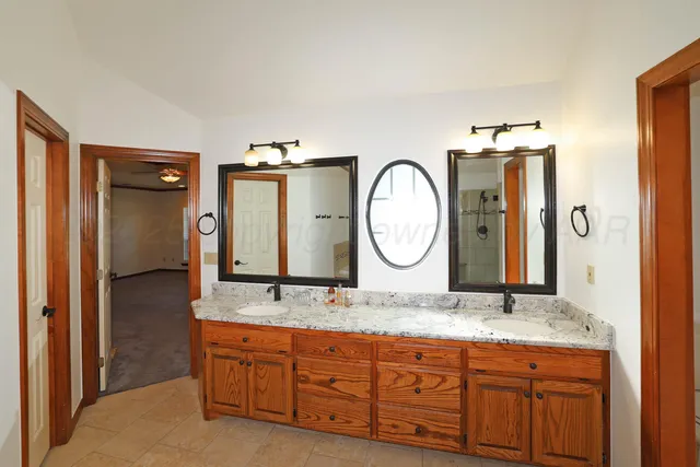 a bathroom with a granite countertop double vanity sink and a mirror