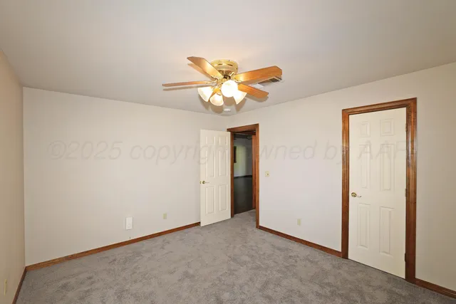 an empty room with closet and a chandelier fan