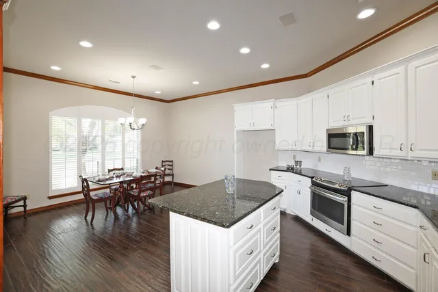 a kitchen with stainless steel appliances granite countertop a stove and a wooden floors