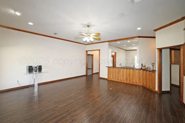 a view of an empty room with wooden floor and a ceiling fan