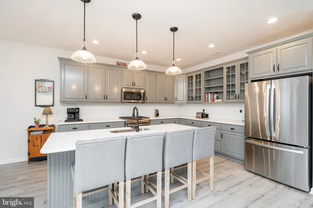 a kitchen with stainless steel appliances granite countertop a sink a stove a refrigerator cabinets and chairs